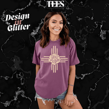 Load image into Gallery viewer, Purple New Mexico Zia glitter t-shirt with rose design worn by smiling woman in denim shorts