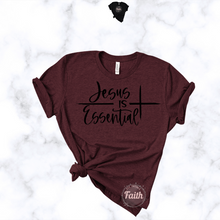 Load image into Gallery viewer, Jesus is Essential t-shirt in maroon with black text and cross design front view with knotted hem